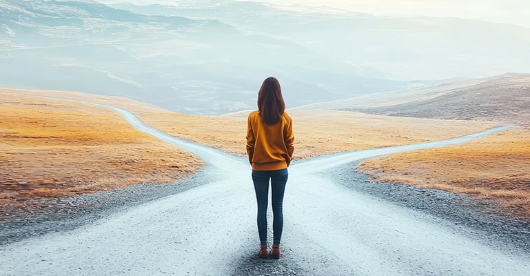 Person standing at a fork in the road, contemplating which path to take.